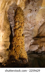 Stalactite-stalagmite Column In Carlsbad Caverns National Park, New Mexico.  Beside Reflecting Pool Of Water.