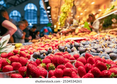 A stall with strawberries and kiwi fruits, with sellers and buyers in the background, at the hall of a local food market in Valencia - Powered by Shutterstock