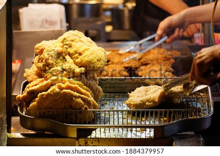 A stall vendor frying in boiling oil the crispy deep-fried chicken cutlets, one of local people's favorite street-foods, in Shilin Night Market, Taipei, where many traditional snacks can be savored