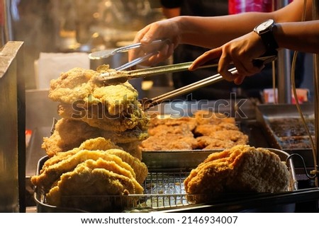 A stall vendor selling crispy deep-fried chicken cutlets, one of local people's favorite street-foods, in Shilin Night Market, Taipei City, Taiwan, where many traditional snacks can be savored