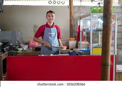 The stall waiter stands holding tongs while preparing the side dishes ordered by the customer at the shop