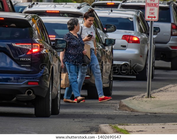 Stamford,\
Connecticut / USA - Circa May 2019:Women crossing a busy Stamford\
street during the afternoon rush hour.\
