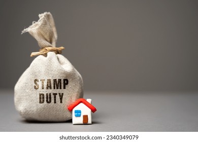 Stamp duty concept. Taxes assessed during the transfer of real estate between two parties. Buying housing and land. Property. Stamp Duty Land Tax SDLT. Money bag and house - Shutterstock ID 2340349079