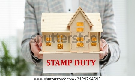 Stamp duty. Woman holding wooden house model, closeup