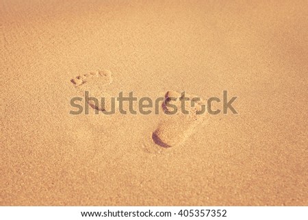 stamp of feet on sand on the beach with sunshine in the morning, vintage color style