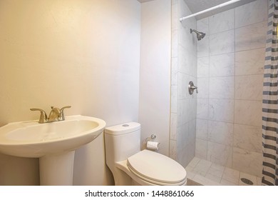 Stand Alone Sink Toilet And Shower Inside A Small Bathrrom With White Wall