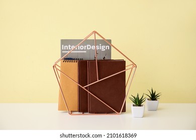 Stand With Books, Notebooks And Magazine On Table Near Color Wall