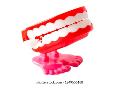 Stand Up Comedy Show, Windup Joke Toy And Prank Toys Concept With A Pair Of Red Wind Up Chattering Teeth With Pink Legs Isolated On White Background With A Clip Path Cutout