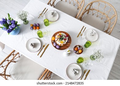 Stand with Easter cake, eggs and dinnerware on served table