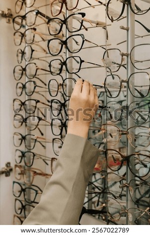 Stand of eyeglasses with different frames in the optical store. Customer chooses eyeglasses with clear lenses from the shelf. Eyesight correction