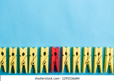 Stand out from the crowd and different concept. Leadership and other similar concepts. One red clothespin stands out from other yellow clothespins on blue background. - Shutterstock ID 1293136684