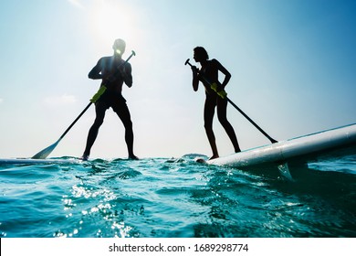 Stand up paddle board couple paddleboarding .Selective focus. People blured with water spray. - Powered by Shutterstock