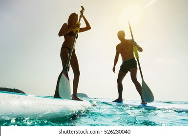 Stand up paddle board couple paddleboarding . Young caucasian couple on summer vacation.