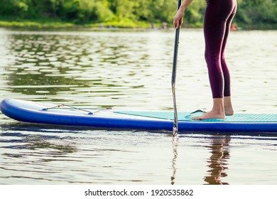 Stand Up Paddle Boarding On A Quiet Sea Lake , Close-up Of Legs And Water Splash