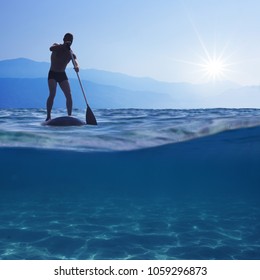 Stand up paddle boarding. Young man floating on a SUP board. Underwater view of sea, copy space for text