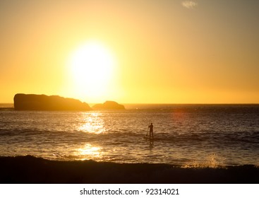 Stand Up Paddle Surfer In Front Of Sunset In The Water