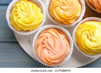 Stand with tasty cupcakes on light blue wooden table, top view - Shutterstock ID 2179388993