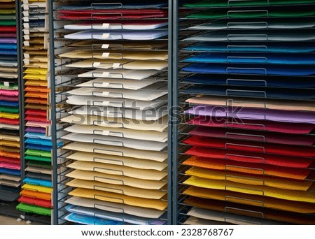 Stand with various color paper on shelves, for design, watercolor painting and pastel drawing, display for sale in school supply or office stationery shop. Cardboard paper for fine art and creativity