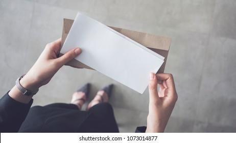 Stand up woman holding white folded a4 paper and brown envelope