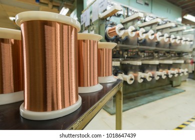 Standard Copper Wire Enamel In A Bobbin On The Table, Steel Floor In The Factory. The Backdrop Is A Machine. Winding Machine