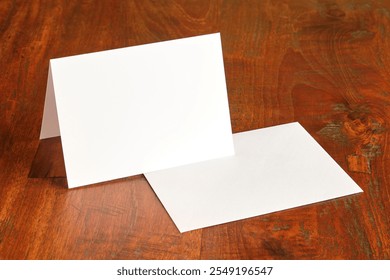 Standing blank empty rectangular greeting card and envelope mock up on dark wooden background with copy space. For use as a Christmas, birthday, wedding or celebration background template.   