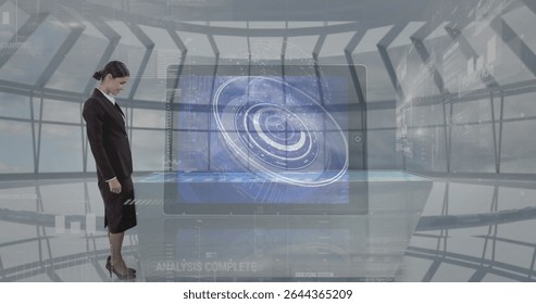 Standing businesswoman examining holographic tabletop display in control center, copy space. Futuristic, innovation, technology, corporate, interface, analytics, professional