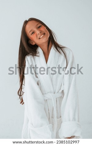 Standing, having fun, in white robe. With eye patches. Conception of beauty and self care. Young girl.