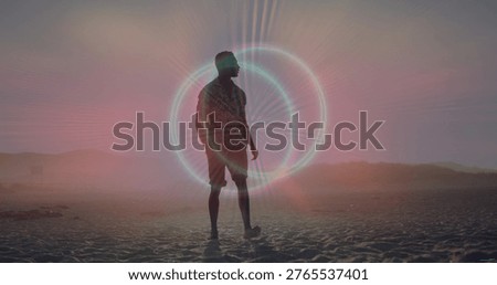 Standing lone man wearing patterned shirt and shorts on sandy beach, halo glowing, footprints. Silhouette, backlit, shoreline, horizon, twilight, pastel, coastal