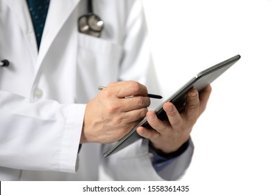 A Standing Male Doctor In Long White Hospital Gown Writing On A Tablet. Isolated On White Background.