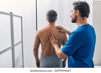 Standing male patient has his spine investigated by osteopath. Osteopath examination - Powered by Shutterstock