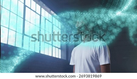 Standing man basking in light in loft with grid window and swirling digital particles, copy space. Minimalist, digitalart, industrial, innovative, contemplative, creative, futuristic