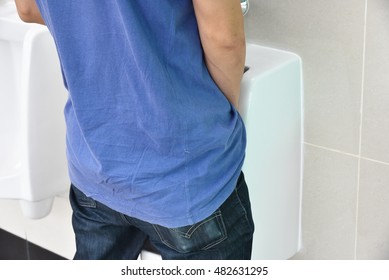 Standing Man Peeing To A Urinal In Restroom