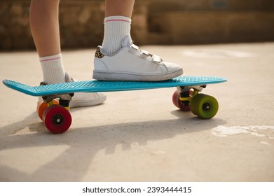 Standing on skateboard on one leg. Cropped view of a little child girl legs in white socks and white sneakers, standing on skateboard on one leg. Kids entertainment. Sport. Leisure activity. Close up - Powered by Shutterstock