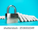 Standing padlock after domino effect chain reaction. Security concept with firmly standing closed lock with pile of fallen domino tiles in background. System toughness and stability concept.