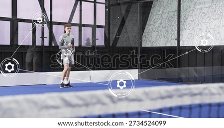 Standing player holding racket, preparing on blue court with digital overlay, wearing sportswear. Athlete, glass, net, facility, lineart, visualization, hitech