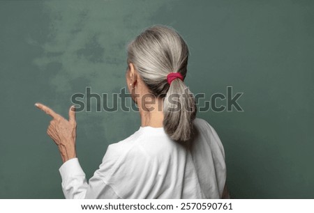  standing and pointing to object on copy space, rear view