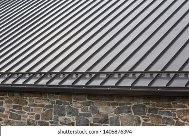Standing seam modern metal roof over vintage stone wall, horizontal aspect