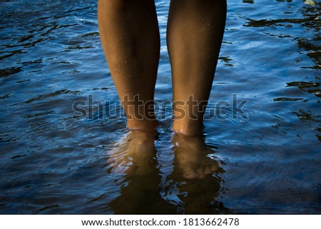 Standing in the stream.
Legs of a young woman in the water. Close up.