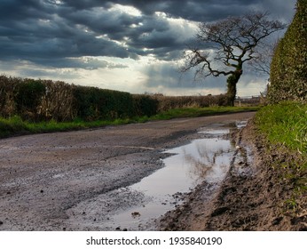 Standing Water In Pot Holes On A Damaged Section Of Country Lane In The North-west UK In Winter. 