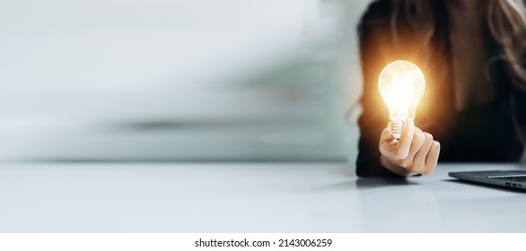Standing woman holding glowing lamp, Creative new idea. Innovation, brainstorming, strategizing to make the business grow and be profitable. Concept execution, strategy planning and profit management. - Shutterstock ID 2143006259