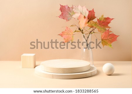 Stands for product of wooden natural materials. Cube, ball and plate as podium for goods. Composition with autumn leaves on beige background.