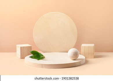 Stands for product of wooden natural shapes. Cube, ball and plate as podium. Creative composition with green leaf on beige background.