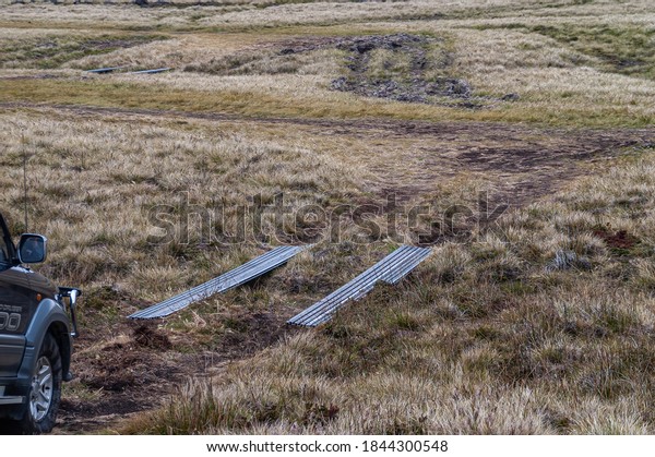 Stanley,\
Falkland Islands, UK - December 15, 2008: Portable and tire-side\
steel plates are needed for cars to drive over soft and wet grassy\
spots, and small brooks in rural\
terrain.