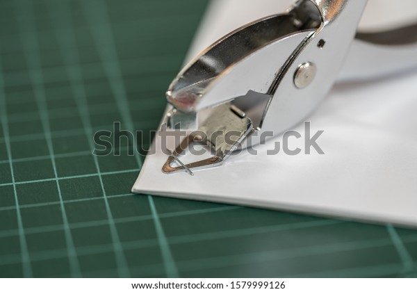 The staple remover is removing the staple from\
the stapled document.