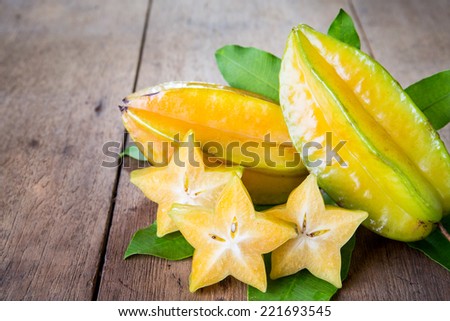 Star fruit with green leaf on wood background .  