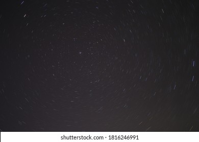 Star Trails On Polaris North Star In Cornwall UK Taken At Night Sky. Light Trail Long Exposure Timelapse Of Stargazing. Galaxy, Milky Way, And Planets Rotating.