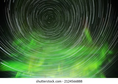 Star trails rotating around the north, with aurora and clouds.