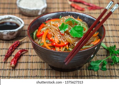 Starch (rice, potato) noodles with vegetables - bell peppers, carrots, cucumber, sesame seeds, cilantro and soy sauce. Vegetarian dish. A delicious lunch or dinner in the Asian style. Cold (hot) salad