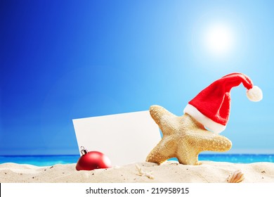 Starfish with Santa hat and a blank paper stuck on a beach on sunny summer day - Powered by Shutterstock