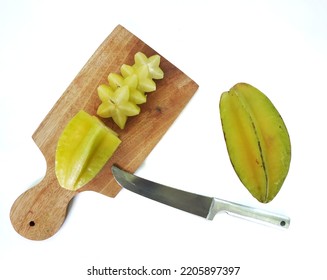 Starfruit cut on the cutting board. And also there is knife and starfruit beside it.